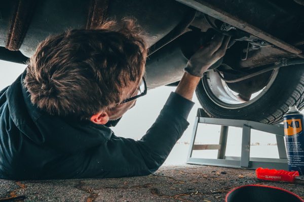 Een monteur die onder de auto ligt