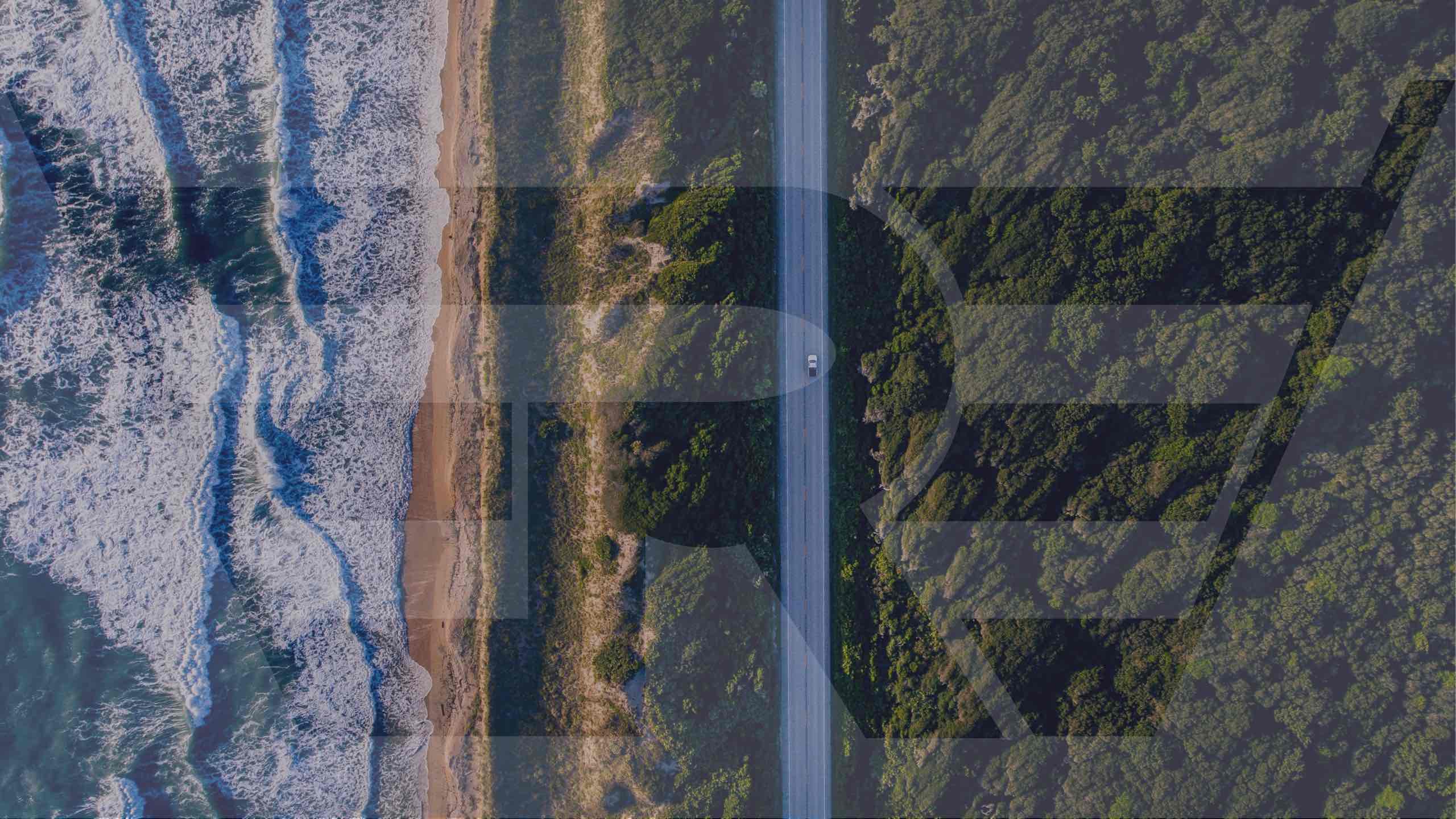 Een blauw auto op een zandweg naast de zee